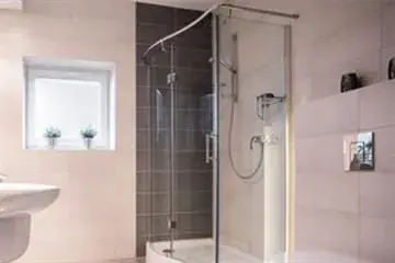 Ein Badezimmer mit ebenerdiger Dusche, Waschbecken, Toilette und Fenster.